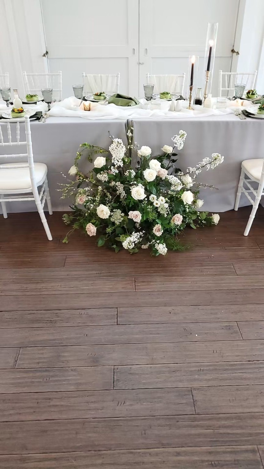 Low white floral arrangement in front of a dining table