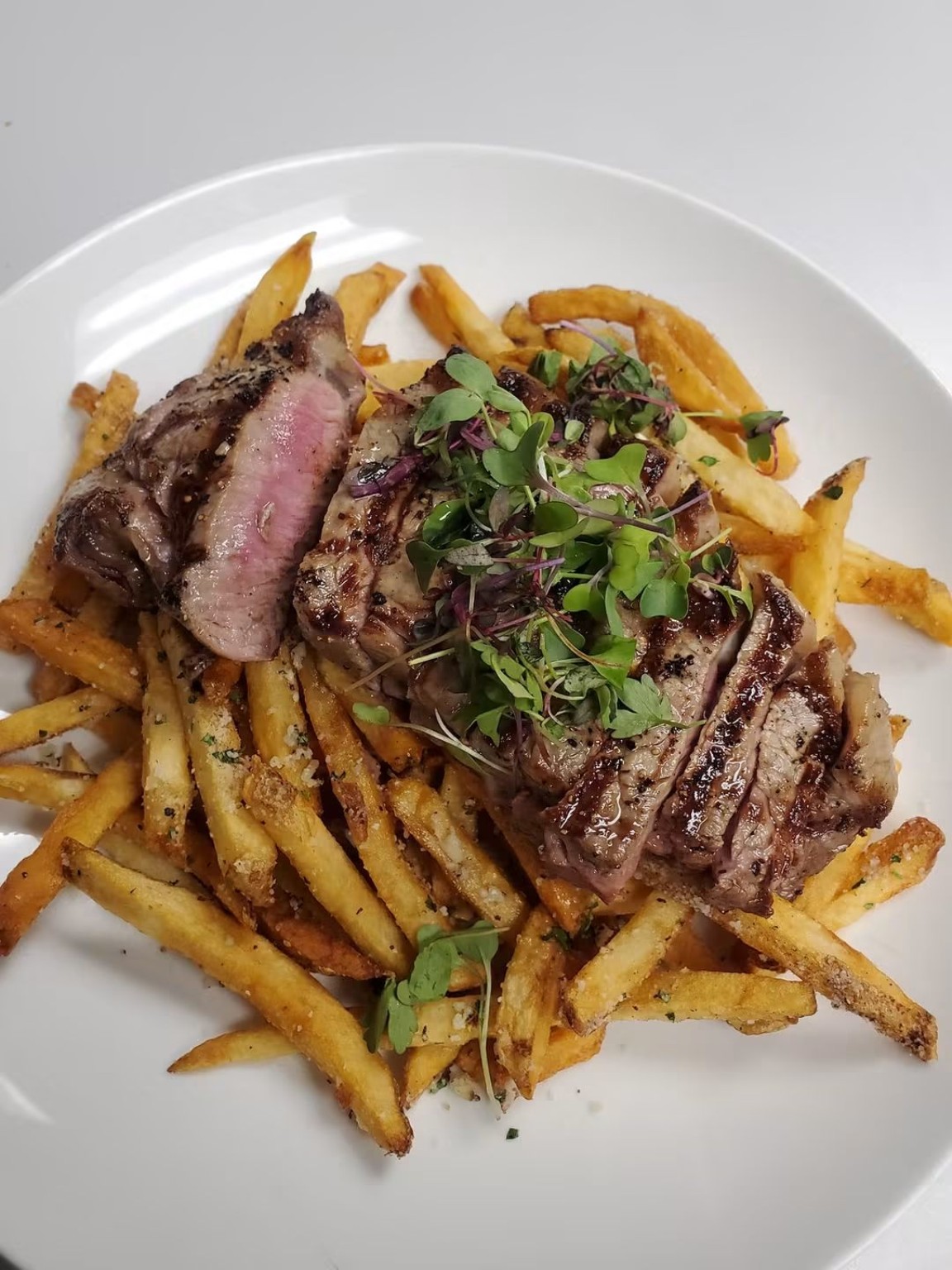 Sliced steak and fries finished with microgreens