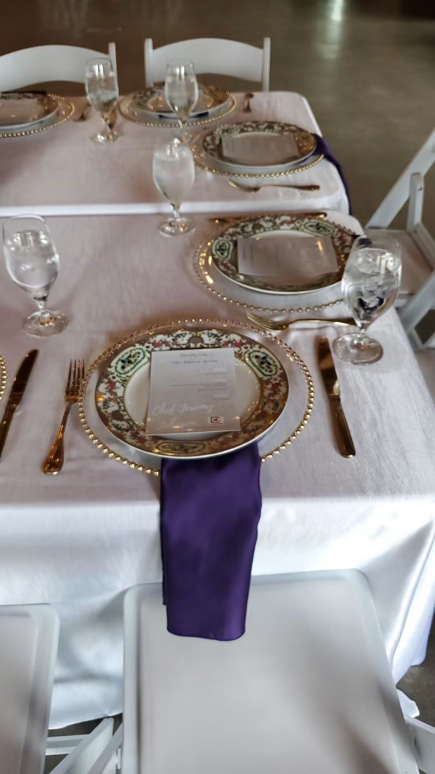 White and gold place setting with purple napkin