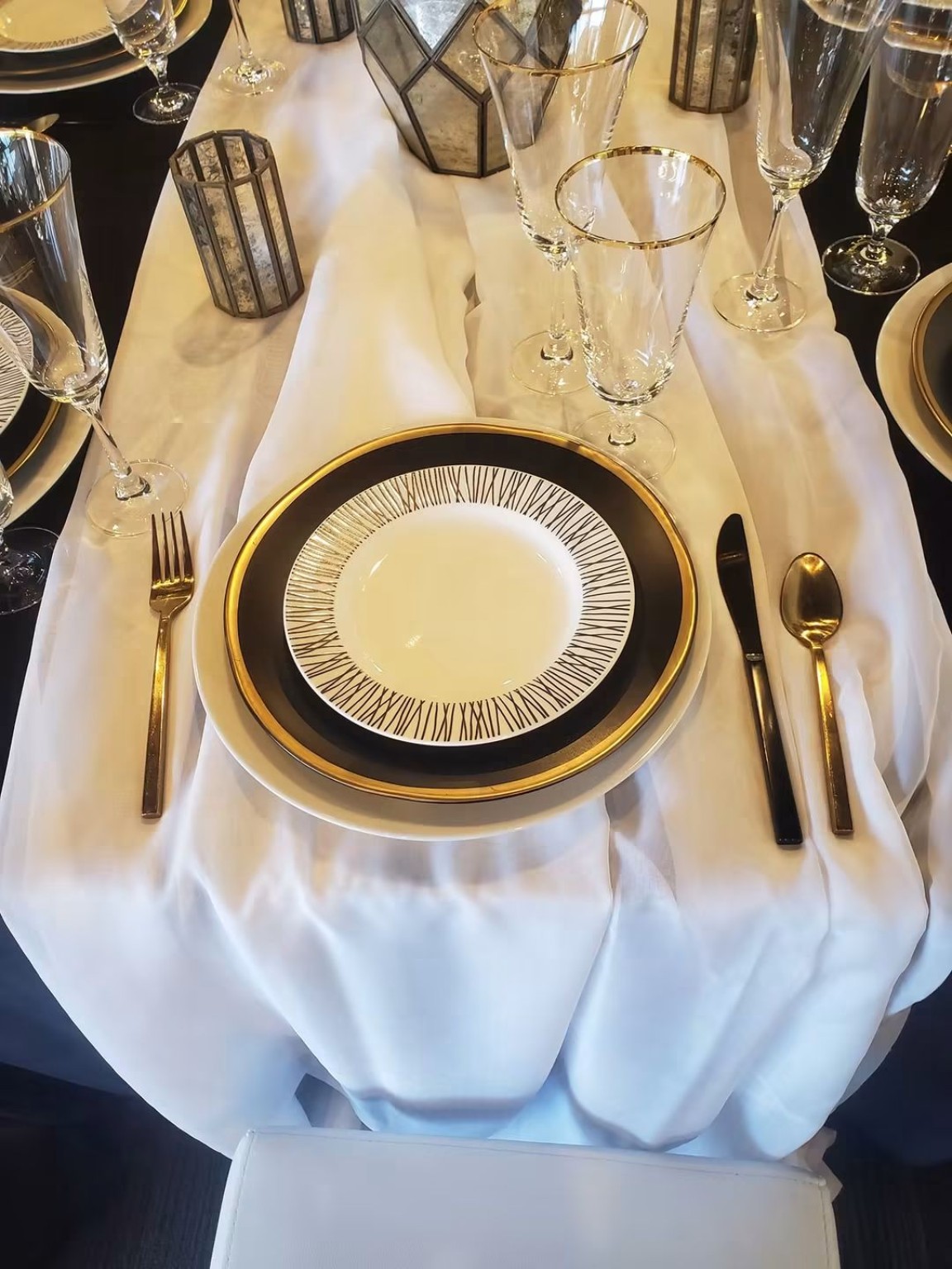 Black white and gold place setting with glassware